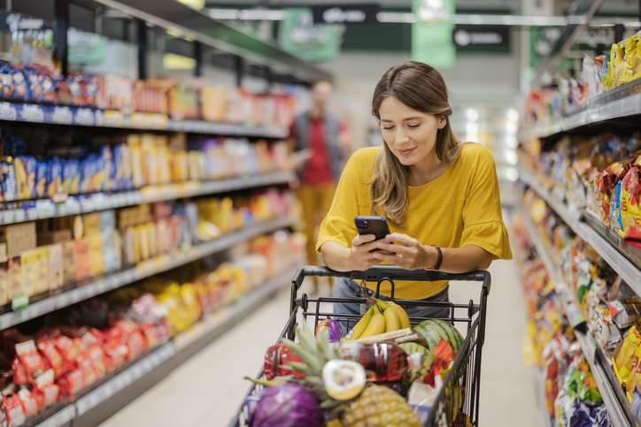 Image of woman in grocery store aisle looking at mobile phone